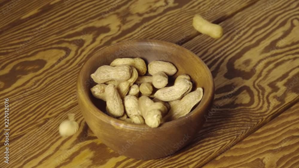 Peanuts fall into wooden cup - Slow motion