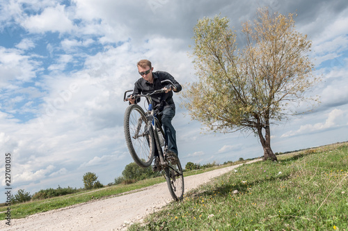 Fototapeta Naklejka Na Ścianę i Meble -  Man riding a bicycle in nature blue sky