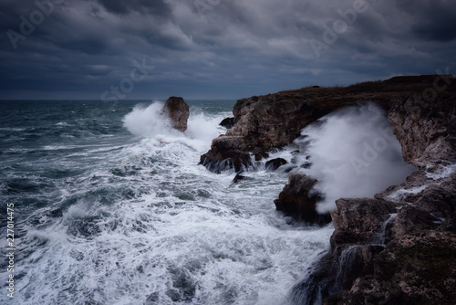 Dramatic nature background - big waves and dark rock in stormy sea, stormy weather. Dramatic scene. Contrasting colors.Beautiful natural landscape, seascape at Tyulenovo, Bulgaria. 