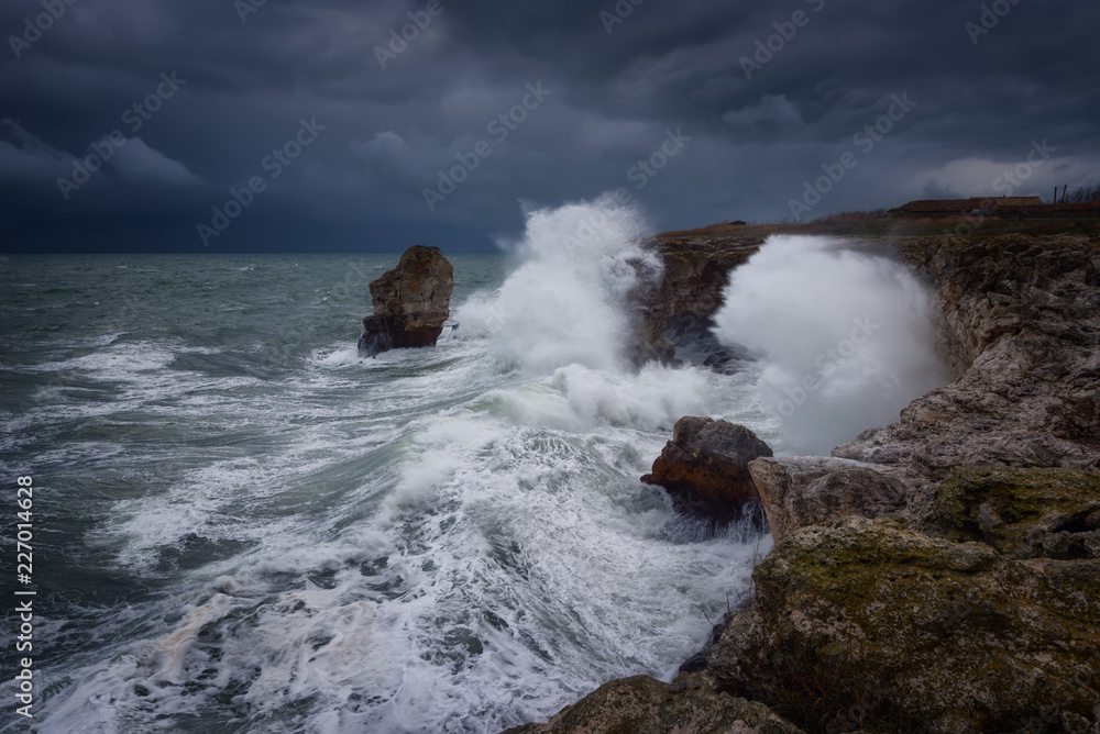Dramatic nature background - big waves and dark rock in stormy sea, stormy weather. Dramatic scene. Contrasting colors.Beautiful natural landscape, seascape at Tyulenovo, Bulgaria. Dramatic nature background - big waves and dark rock in stormy sea, stormy weather. Dramatic scene. Contrasting colors.Beautiful natural landscape, seascape at Tyulenovo, Bulgaria.