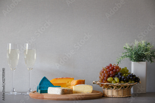 Cheese and grapes in wicker basket with white wine
