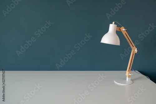 Office work desk with office lamp in a dark blue green background. White desk with copy space photo