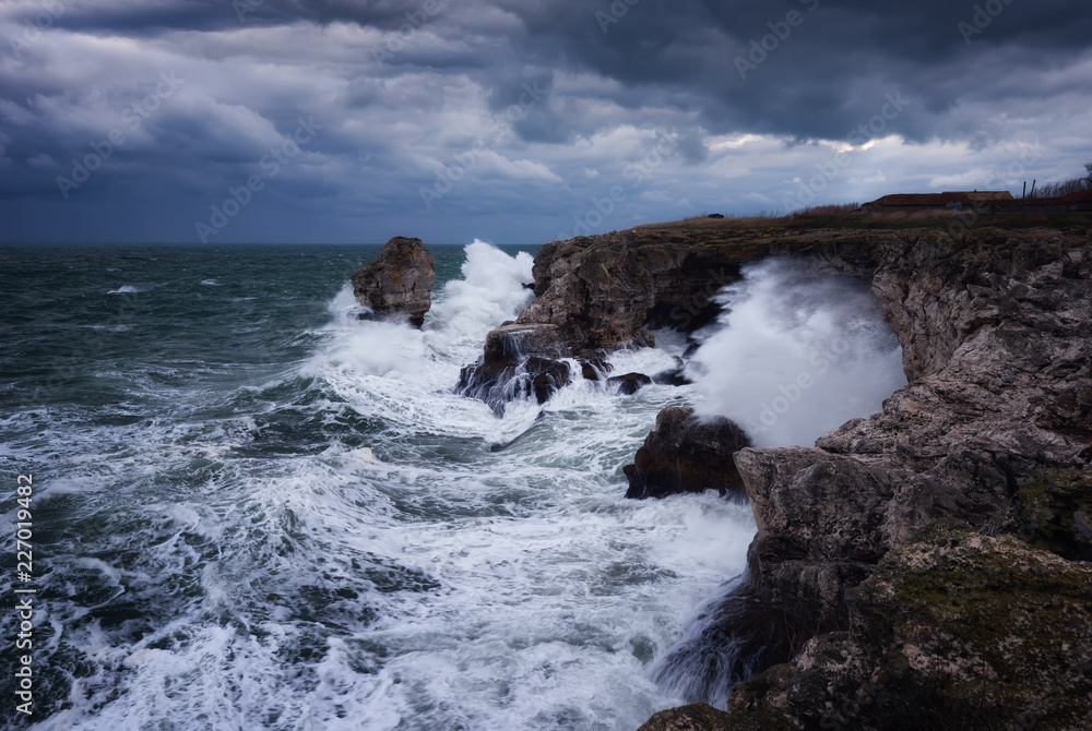 Dramatic nature background - big waves and dark rock in stormy sea, stormy weather. Dramatic scene. Contrasting colors.Beautiful natural landscape, seascape at Tyulenovo, Bulgaria. 