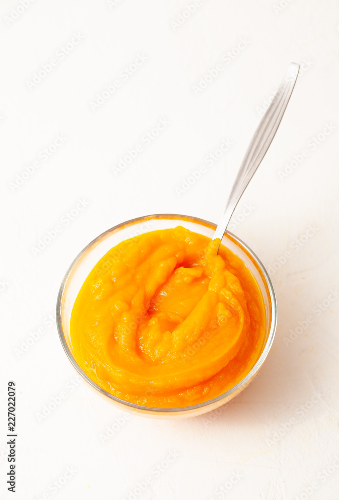 Fotografie Pumpkin puree in glass bowl on white background.