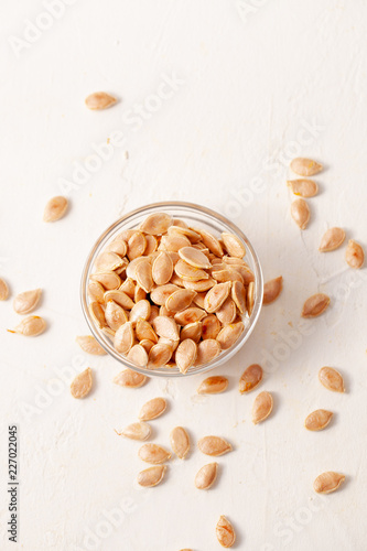 Roasted pumpkin seeds in a glass bowl on white