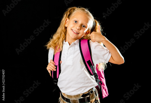 Funny cute primary student girl with backpack jumping and having fun