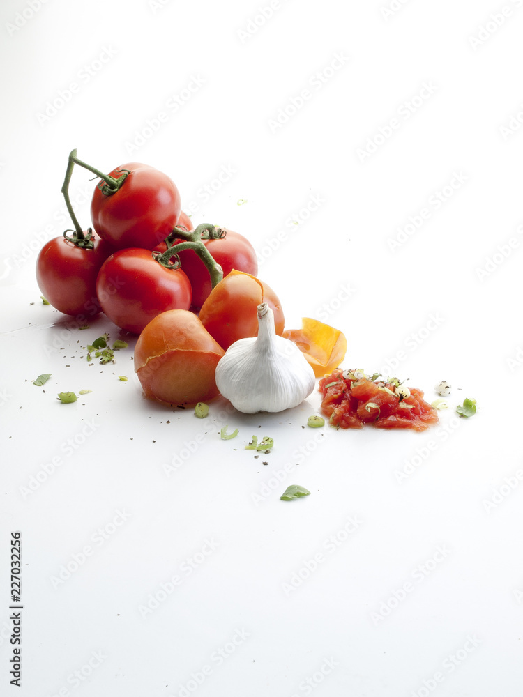 Bodegón de tomates rama, ajo, cebollino visto cenitalmente