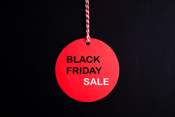 Black friday sale concept. Fourth Friday of November, beginning of Christmas shopping season since 1952. Red tag with black text on bright red background. Copy space, close up, top view, flat lay.