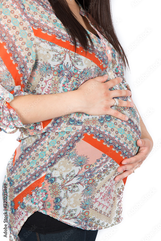 Pregnant woman in fashion clothes caressing her belly over white background
