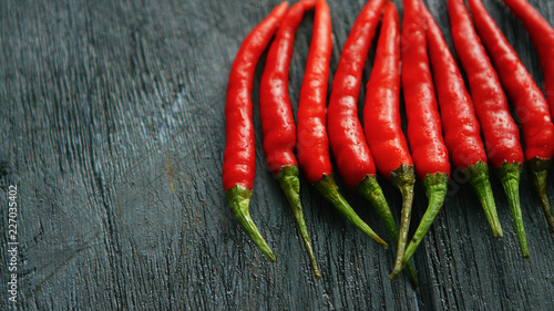 From above shot of layout of bright ripe red chili peppers arranged in row on rough wooden table