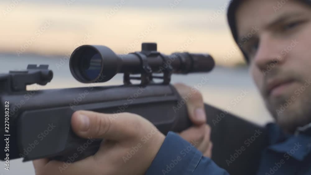 Close up of hunter aiming down his rifle in autumn season Close up of hunter aiming down his rifle in autumn season