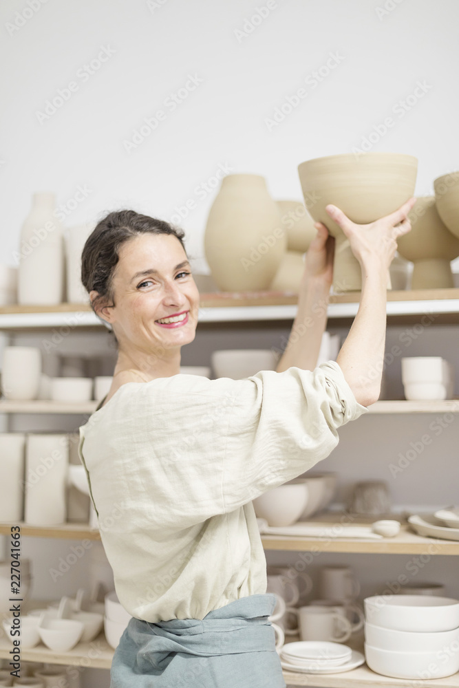 Ceramist woman holding a potter in her studio Ceramist woman holding a potter in her studio