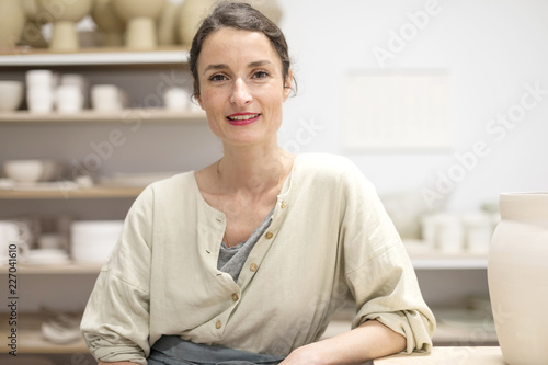 Woman in work wear in her workshop by table with handmade items