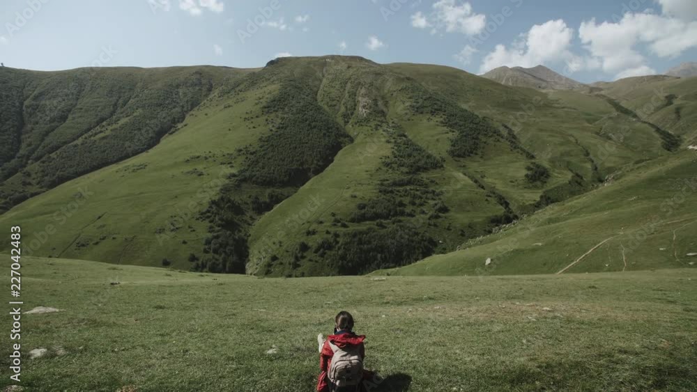 Female traveler sits on hill above the mountain gorge. Young woman highland mountain landscape Female traveler sits on hill above the mountain gorge. Young woman highland mountain landscape
