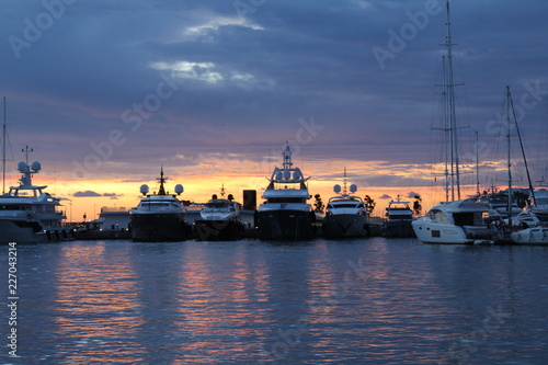Sunrise in Ibiza port: colored sky and luxury yachts in the background