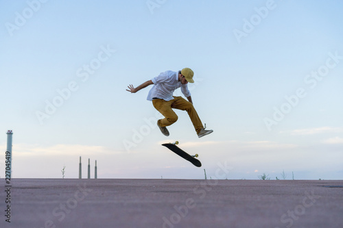 Young man doing a skateboard trick on a lane at dusk photo