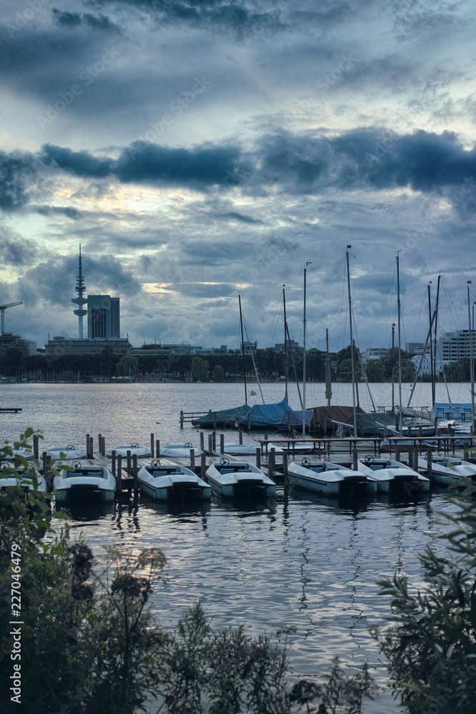 Small sailing boats on the Alster in Hamburg dramatic sky pedalo