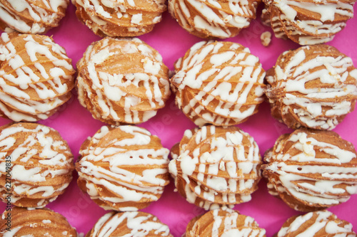 A number of brown donuts on a lilac background. 