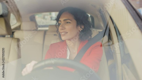 Portrait of beautiful Young Woman Driving Car through big Sunny City. Camera Shot Made From the Front Windshield. photo