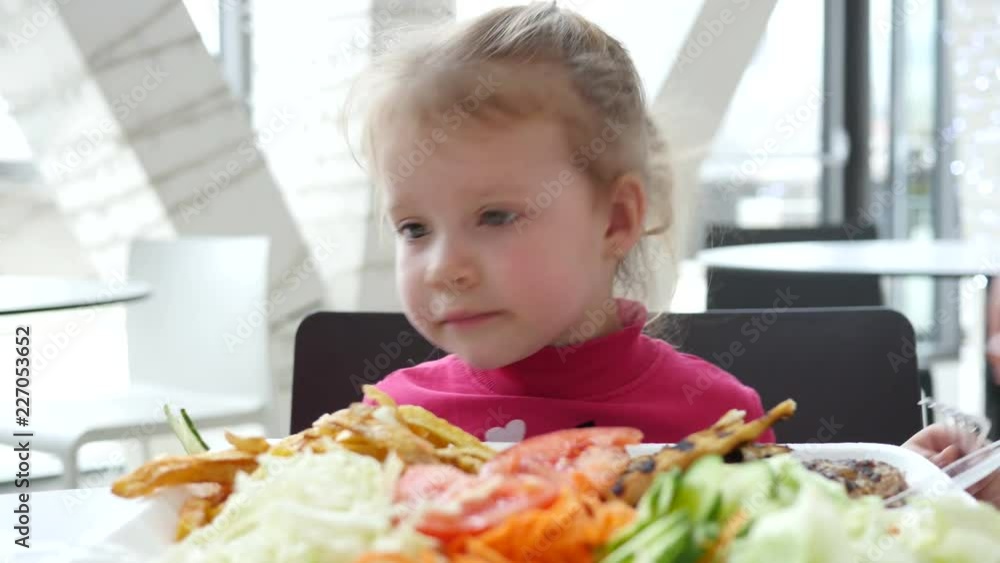 Cute little child girl eating vegetables instead of meat in fast food cort Cute little child girl eating vegetables instead of meat in fast food cort