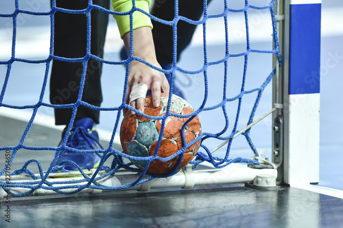 Hand of handball goalkeeper takes the ball from the goal.