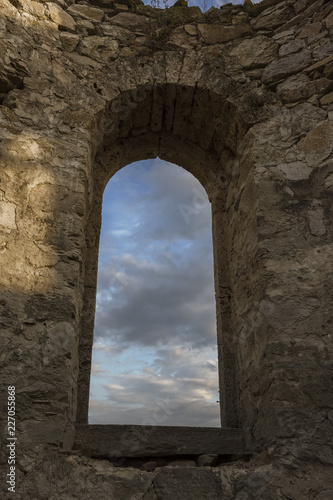 Beautiful colorful clouds on blue sky on sunset. View through arched window in old stone abandoned church.   rchitecture concept.