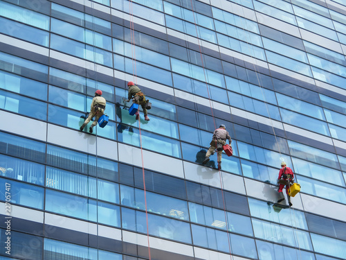 Climbers clean windows on the side of an office building