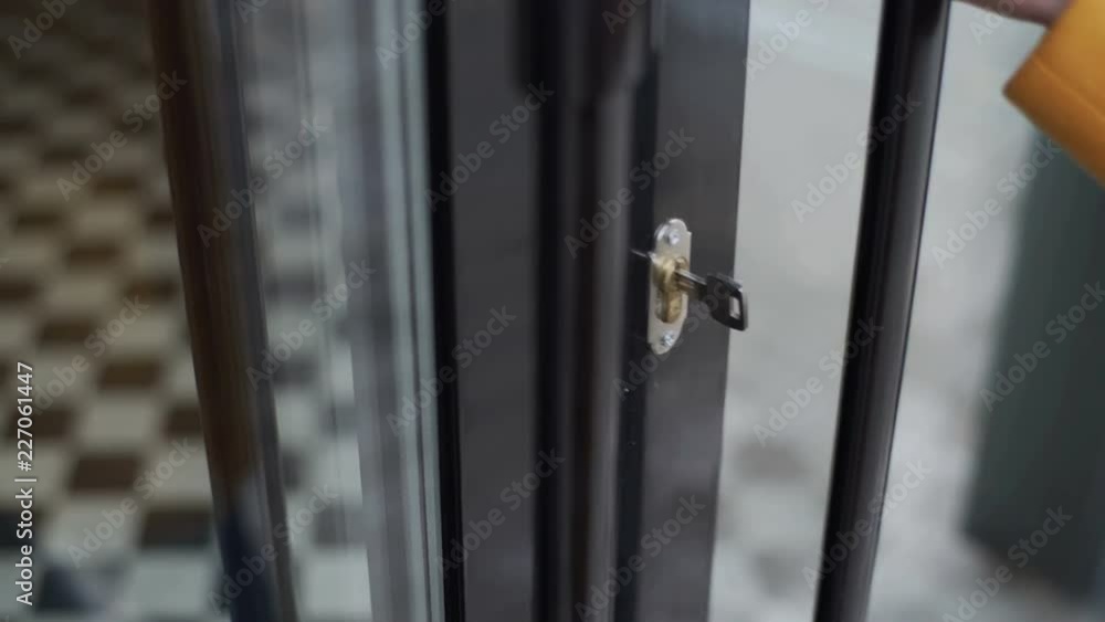 Woman in a yellow coat opens the door of a cafe with a key. Woman in a yellow coat opens the door of a cafe with a key.