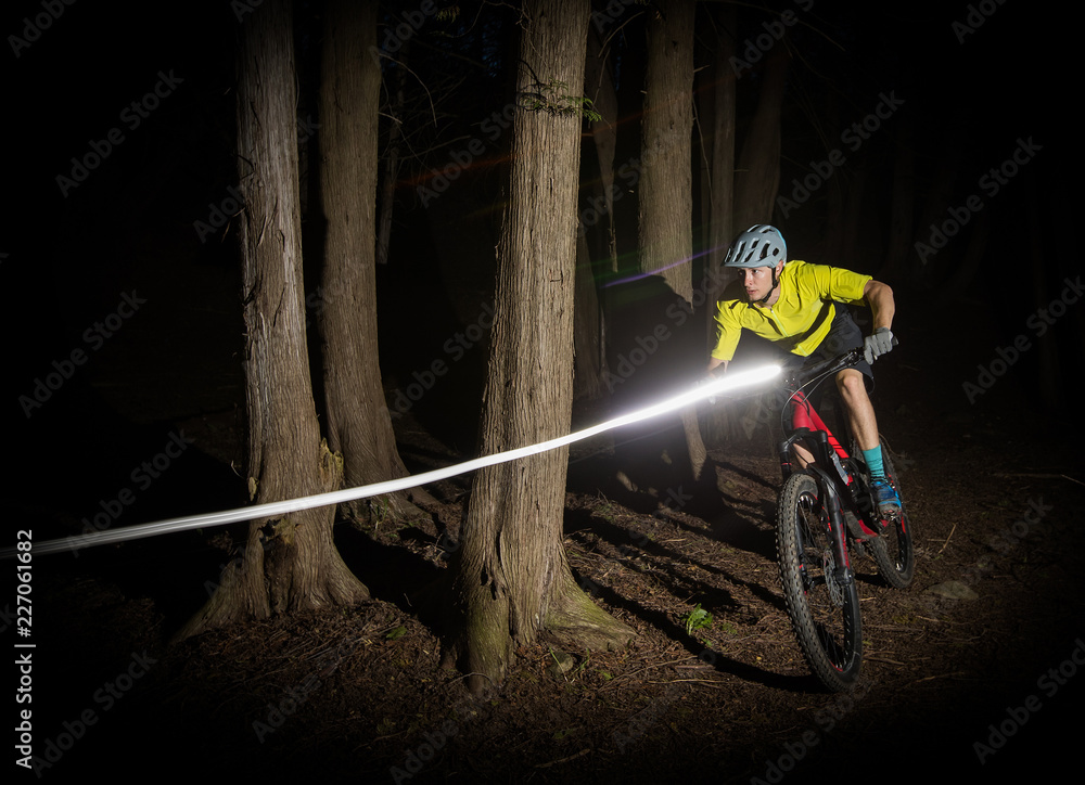 Man riding a mountain bike at night with lights.