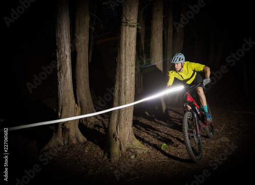 Obraz na płótnie Man riding a mountain bike at night with lights. w salonie