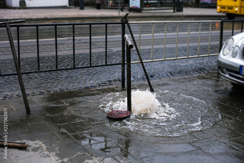 Broken sewer on city street. Water flows out of manhole photo