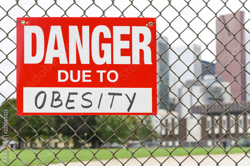  Sign danger due to obesity hanging on the fence
