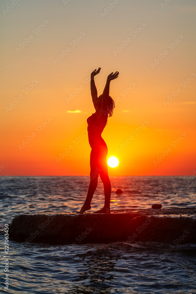 Silhouette of a girl at sunset on the sea