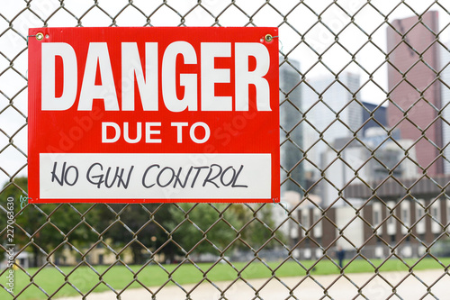  Sign danger due to no gun control hanging on the fence