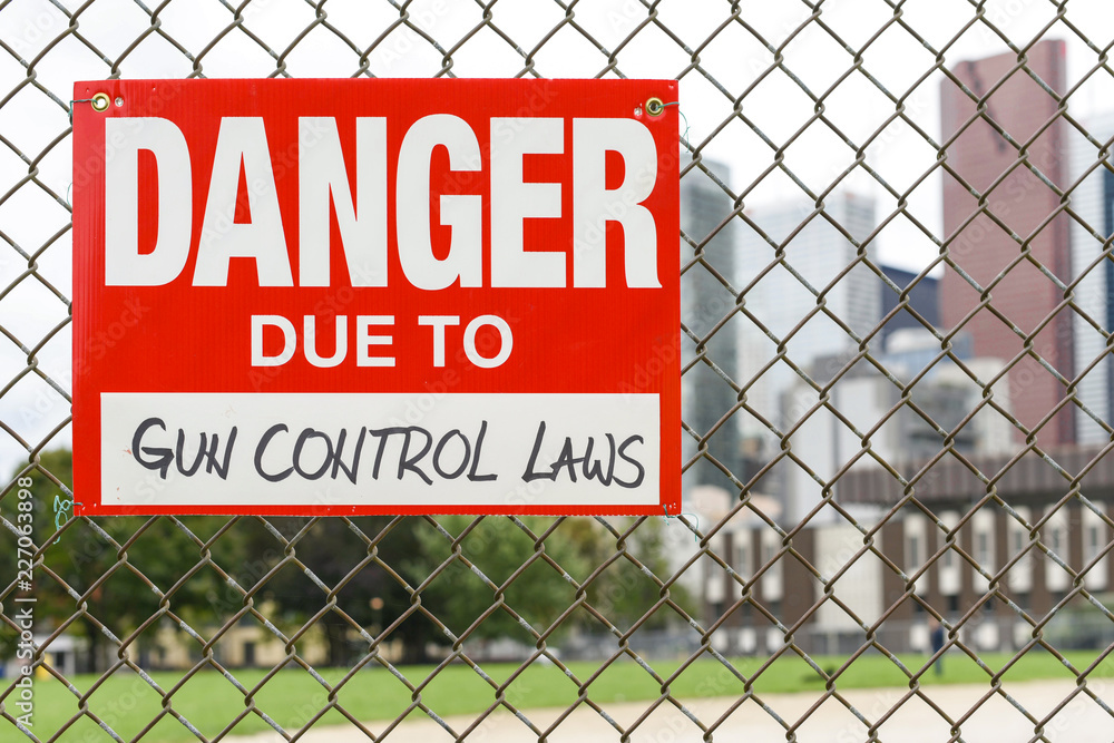Sign danger due to gun control laws hanging on the fence Sign danger due to gun control laws hanging on the fence