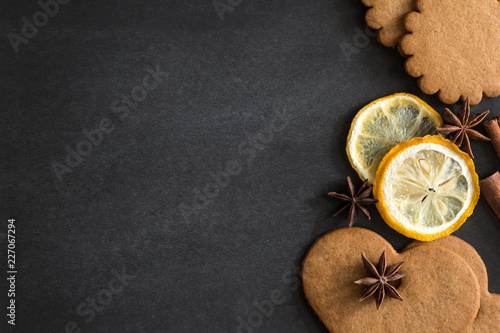 Черный фон, на котором лежат сушеные лимоны или апельсины и имбирное печенье photo