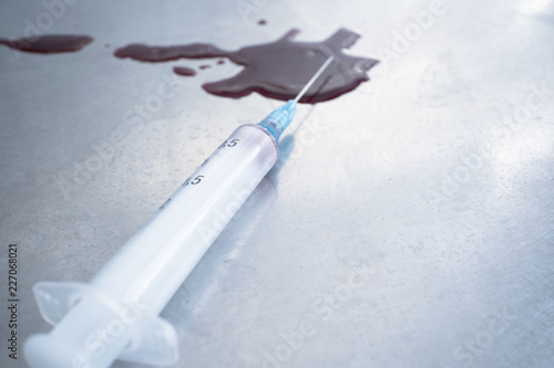 syringe with blood and a puddle of blood on the medical table