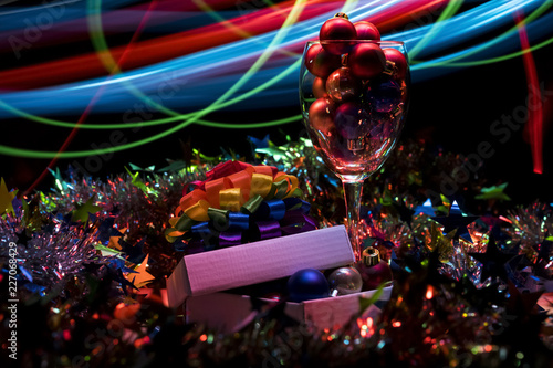 Christmas.Glass with red balls. Christmas tinsel. Blue and red blurred stripes. Light effect