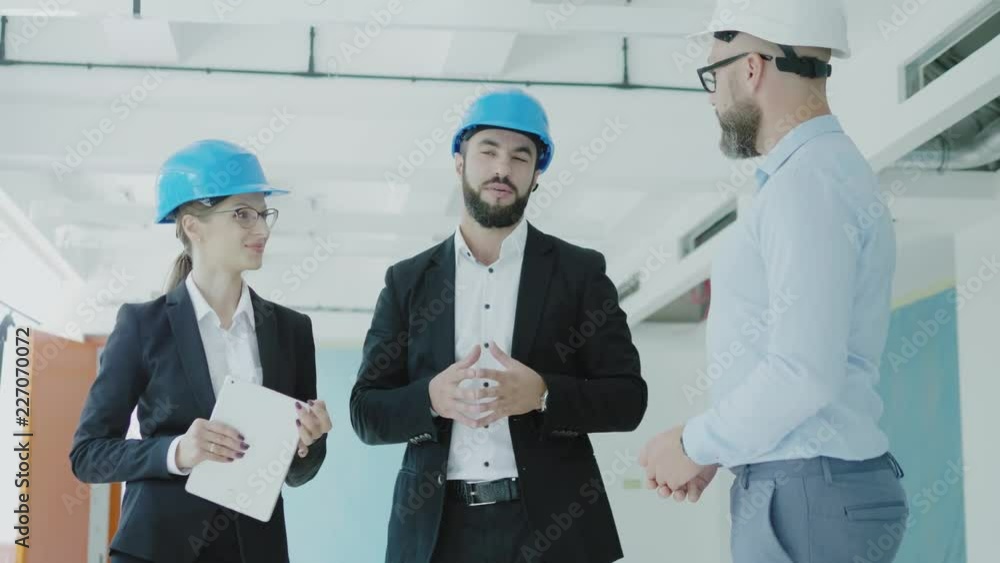 Engineers in hardhats have conversation in a factory Engineers in hardhats have conversation in a factory