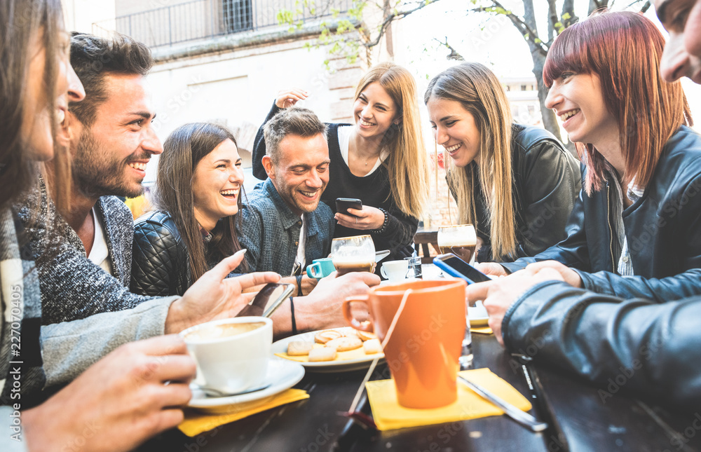 Happy friends talking and having fun with mobile smart phones at restaurant drinking cappuccino and hot tea - Young people together at cafeteria - Friendship concept with men and women at coffee bar Happy friends talking and having fun with mobile smart phones at restaurant drinking cappuccino and hot tea - Young people together at cafeteria - Friendship concept with men and women at coffee bar