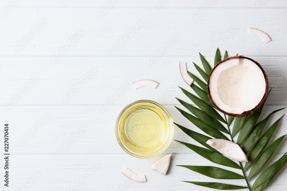 coconut oil, coconuts and green tropical leaves on wooden background. Top view. coconut oil, coconuts and green tropical leaves on wooden background. Top view.