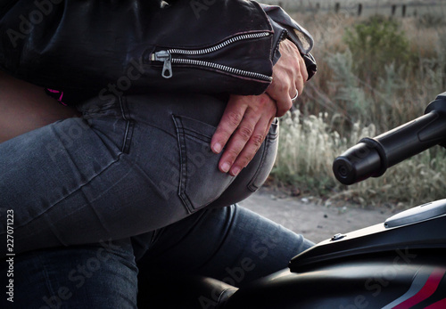 hands of a biker man hugging a biker woman s back sitting on a motorcycle