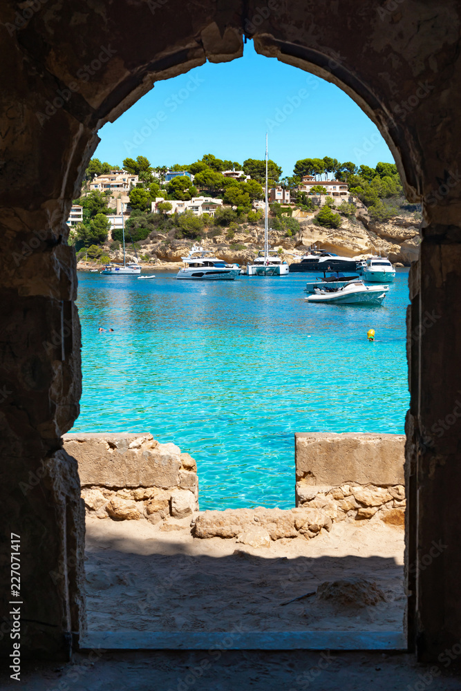 View through a ruin door to the emerald green bay of Portals Vells  |  Mallorca  |  9526