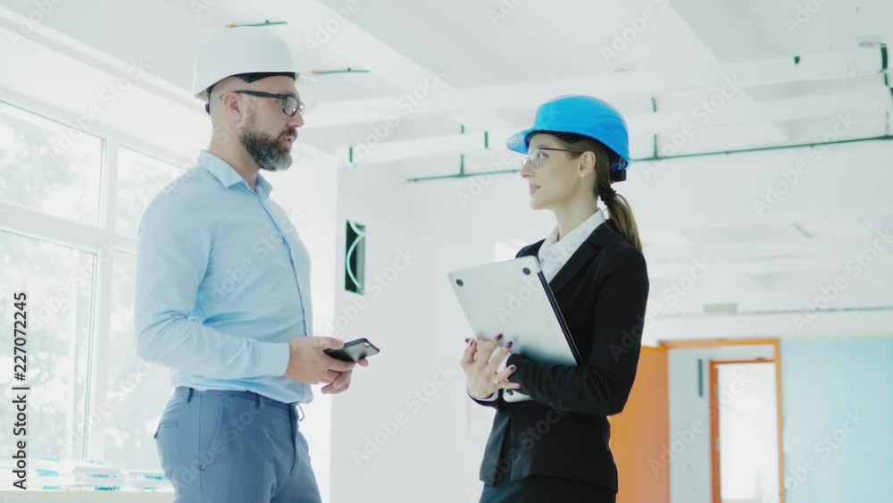 Engineers in hardhats have conversation in a factory Engineers in hardhats have conversation in a factory