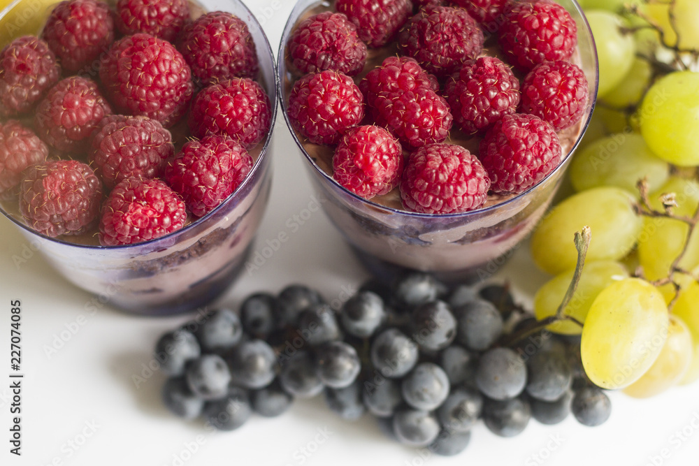 a hand with a beautiful manicure holds a cake in a Cup with berries and chocolate a hand with a beautiful manicure holds a cake in a Cup with berries and chocolate