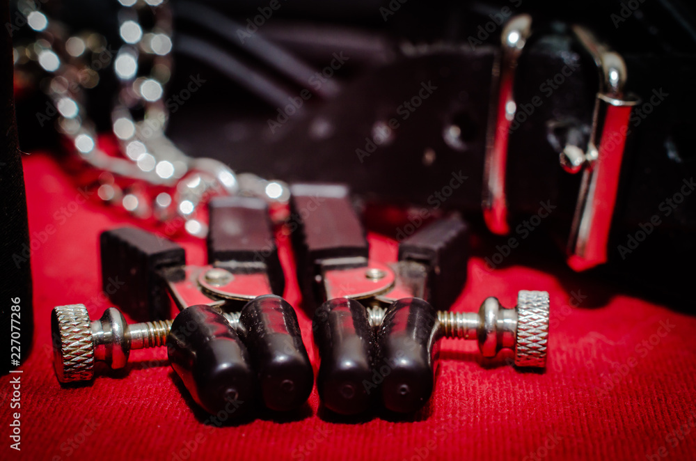 Naklejka premium bdsm accessory human collar and accessory nipple clasp with metal chain on a red background close-up