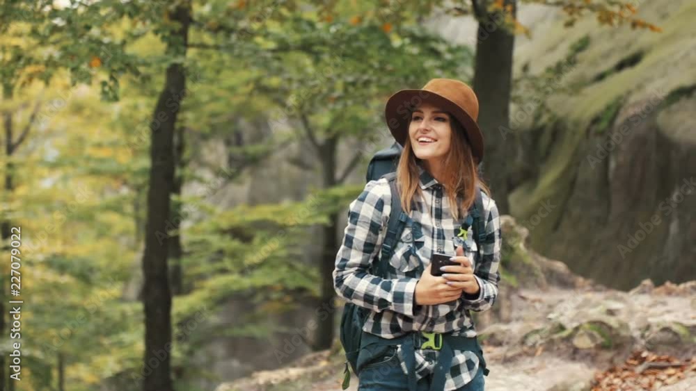 Contented, fit girl taking picture of nice view while looking around the location in fascinating, mountain woods