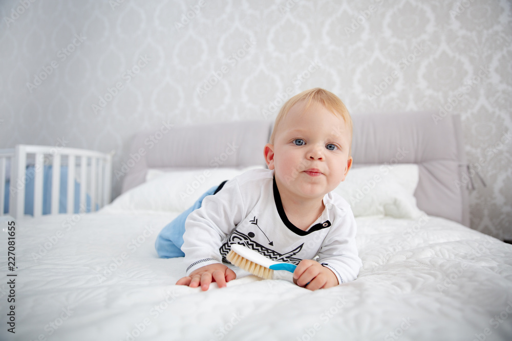 Playful little boy wearing blue pyjamas in bed