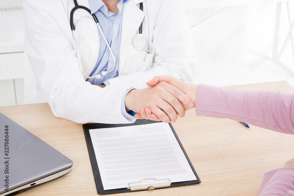 male hand of the doctor shakes the female arm of his patient in clinic, medical office. Healthcare concept, health insurance male hand of the doctor shakes the female arm of his patient in clinic, medical office. Healthcare concept, health insurance