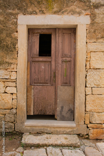 An old wooden door in a derelict sstone building in the Croatian hill village of Bale, also called Valle 